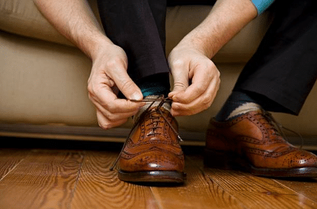 homme nouant ses lacets de chaussures