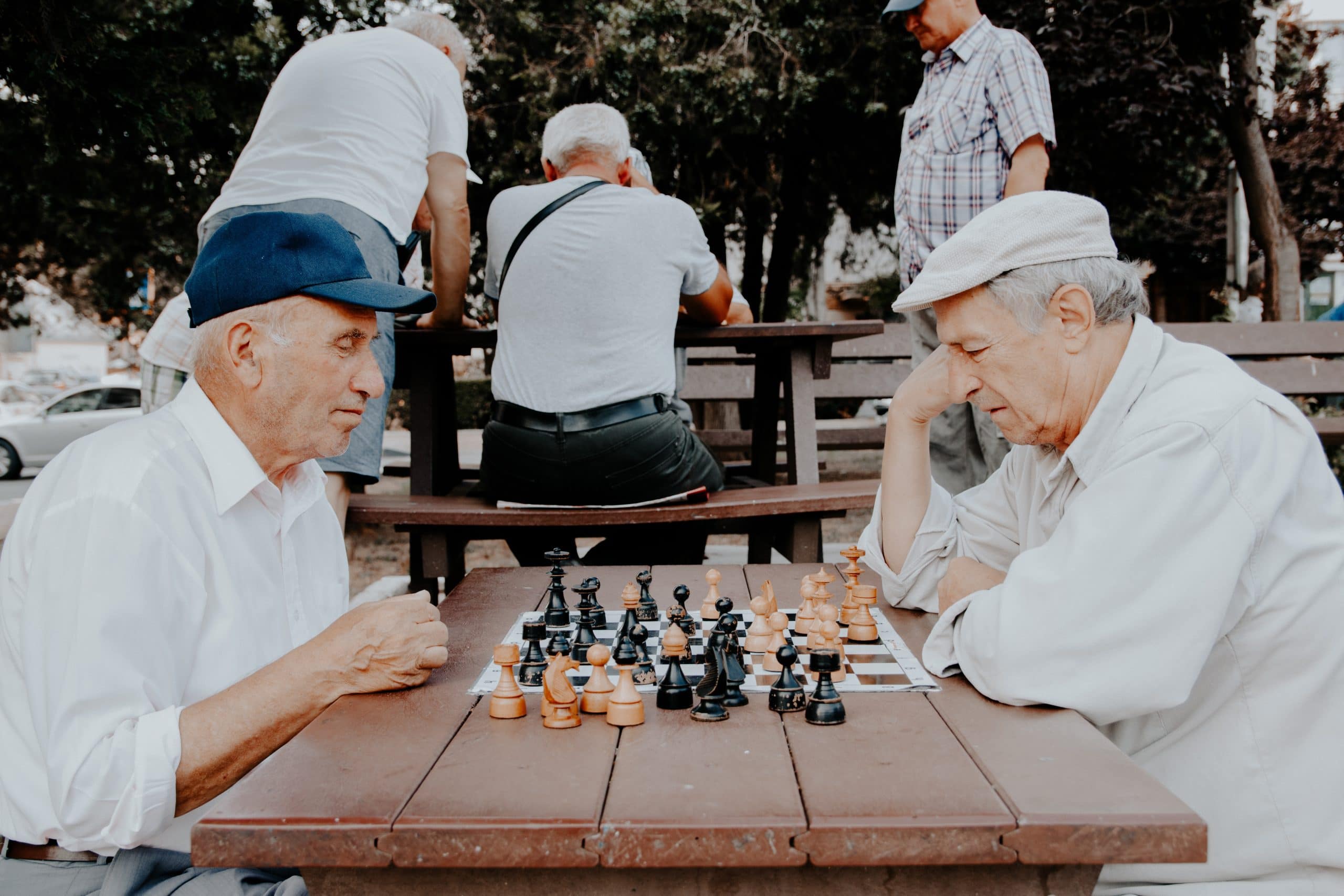 Deux personnes âgées qui jouent aux échecs à l'extérieur.