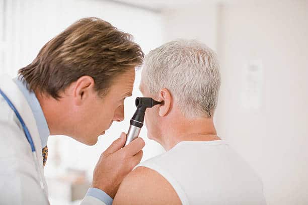 Médecin ORL qui réalise un examen auditif sur une personne âgée souffrant de troubles auditifs