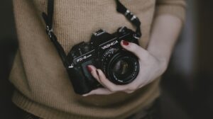 appareil photo noir tenu dans une main de femme avec du vernis