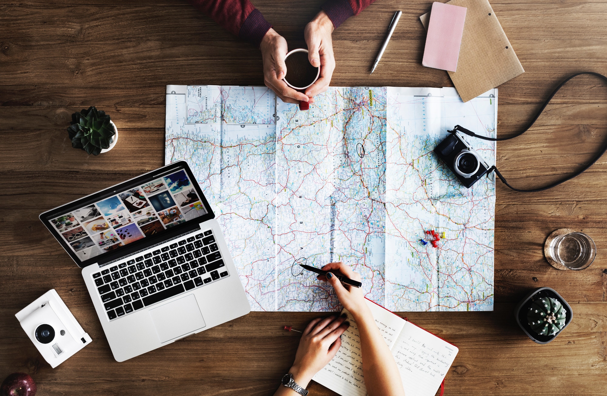 vue de haut d'une carte sur une table avec appareil photo carnets ordinateur une personne tien un café et une autre un stylo