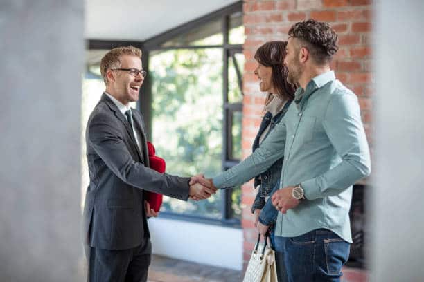 Agent immobilier serrant la main à un couple d'acheteur