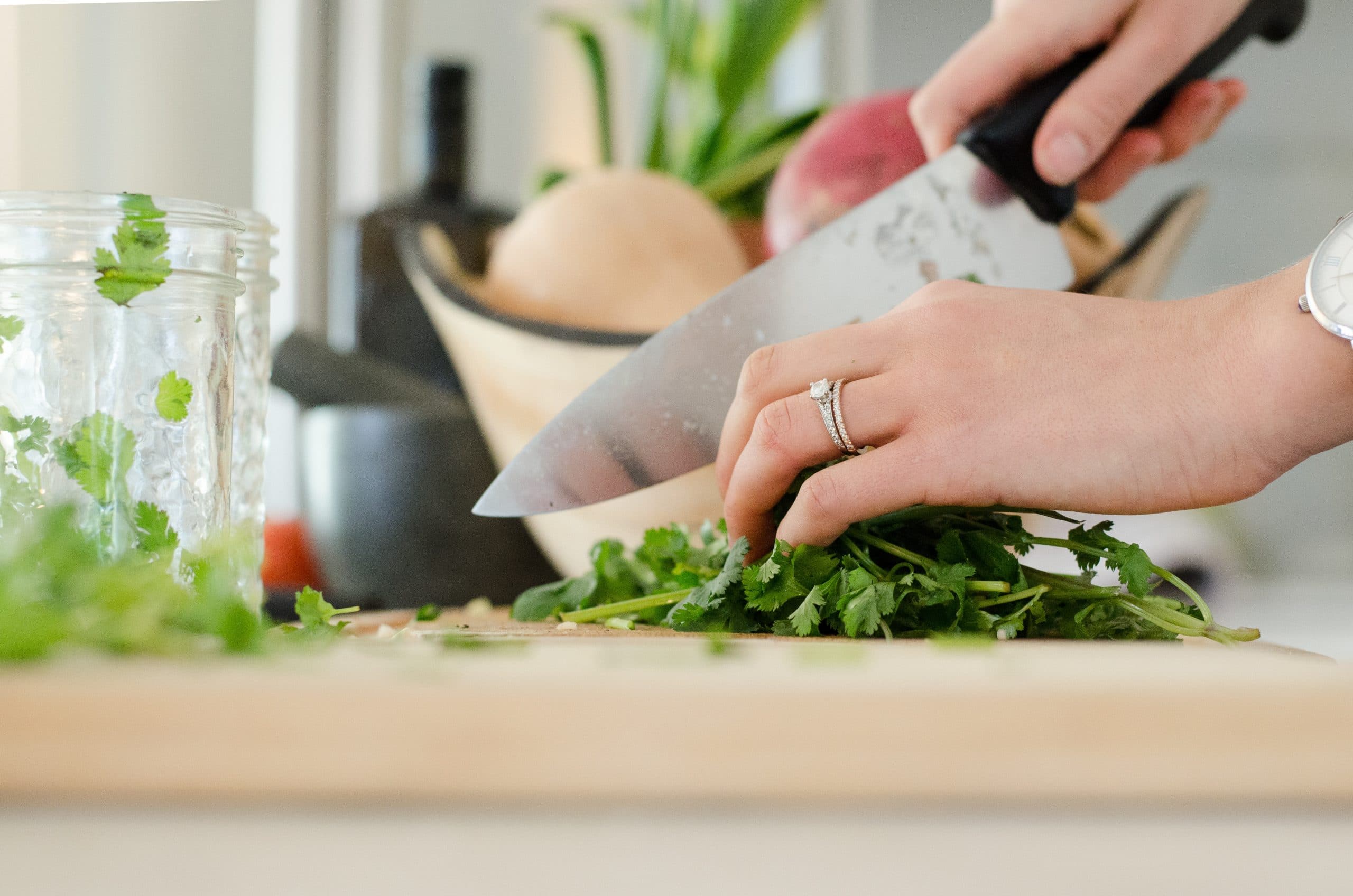 personne découpant des herbes aromatiques avec un couteau de cuisine