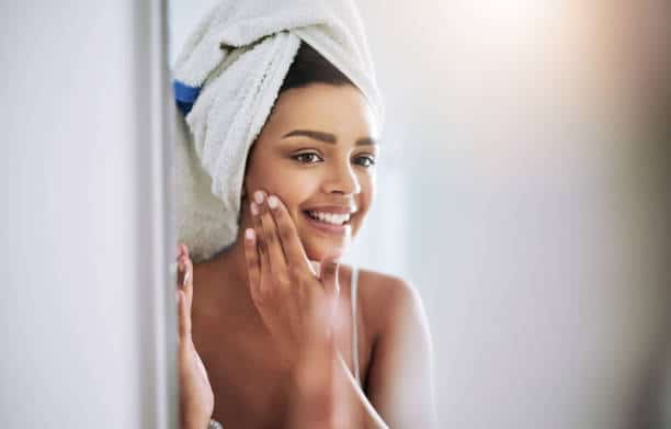 Jeune femme qui s'applique de la crème sur le visage