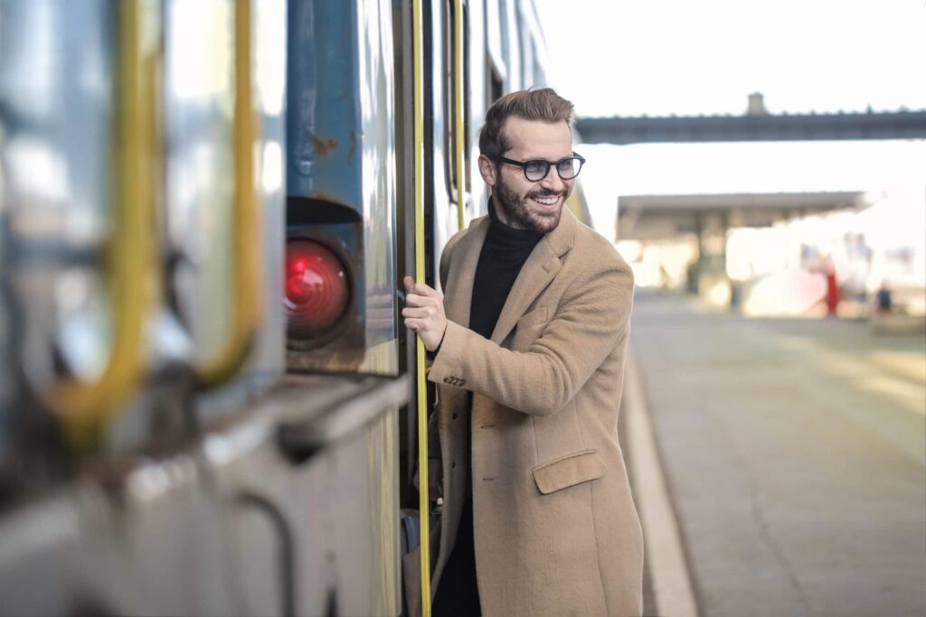 homme portant un pull noir et un manteau long beige