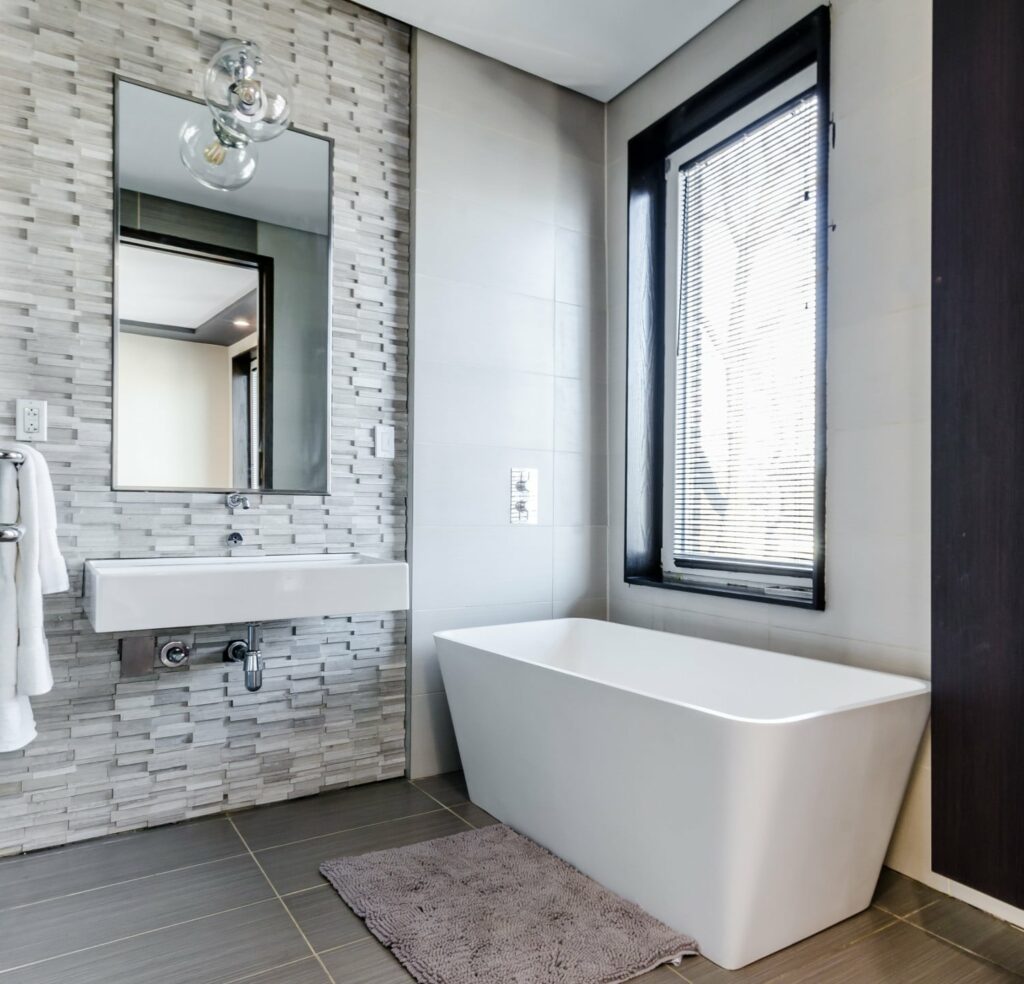 salle de bain avec baignoire rectangle mur avec effet graphique et carrelage foncé au sol