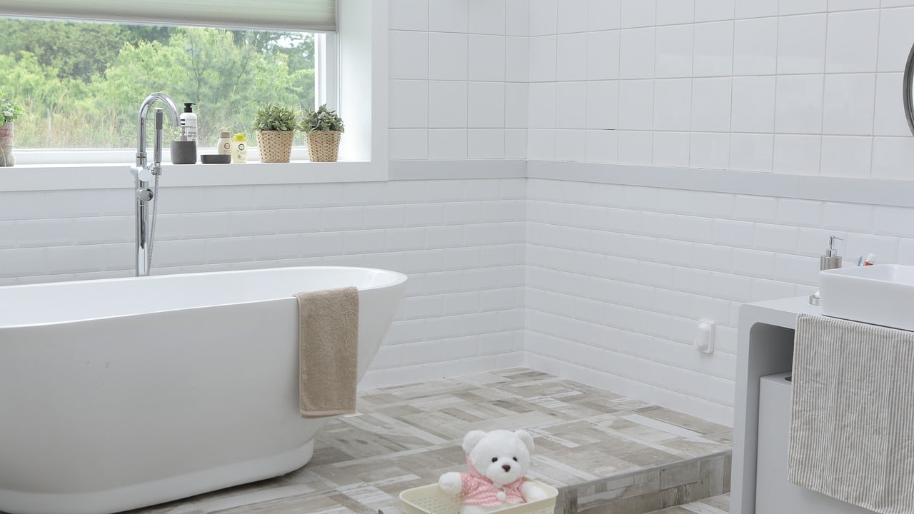 salle de bain avec baignoire carrelage blanc au mur et bois au sol
